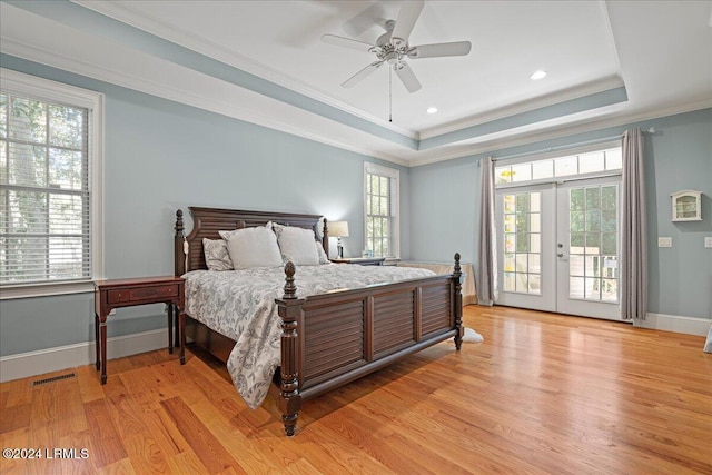 bedroom featuring french doors, multiple windows, and a tray ceiling