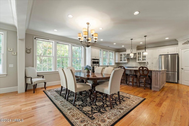 dining space with ornamental molding, sink, an inviting chandelier, and light hardwood / wood-style floors