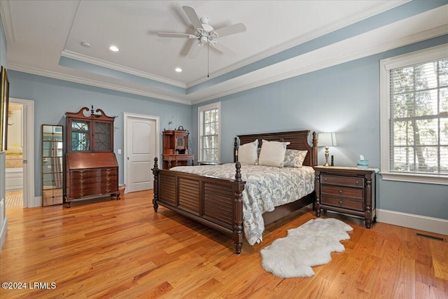 bedroom featuring ensuite bathroom, ornamental molding, a tray ceiling, ceiling fan, and multiple windows