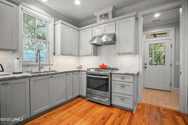 1108 12th St, Port Royal, SC 29935 - kitchen featuring stainless steel gas range oven, under cabinet range hood, gray cabinetry, ornamental molding, and light wood-style floors