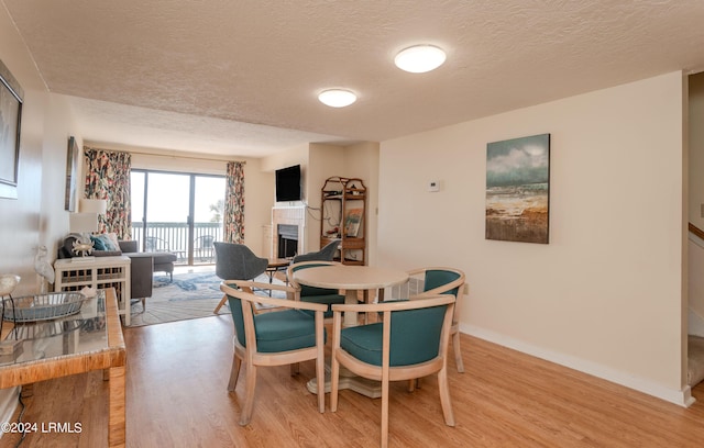 dining space with light hardwood / wood-style floors and a textured ceiling