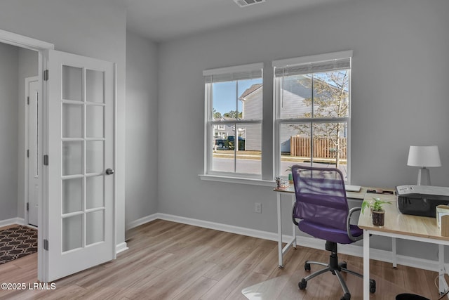 office space featuring light wood-type flooring, visible vents, and baseboards