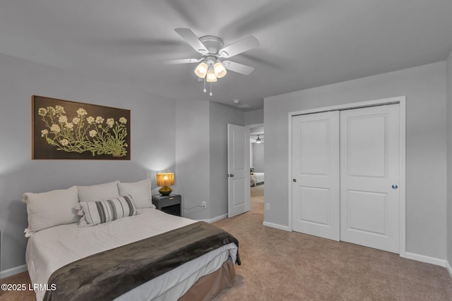 bedroom with baseboards, a closet, and light colored carpet