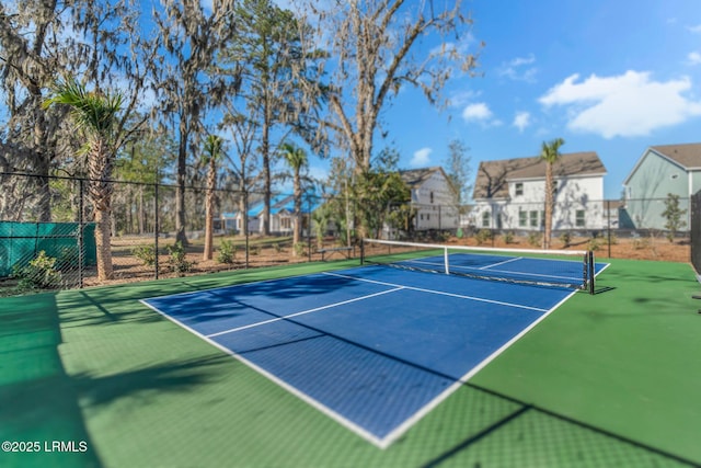 view of tennis court featuring a residential view and fence