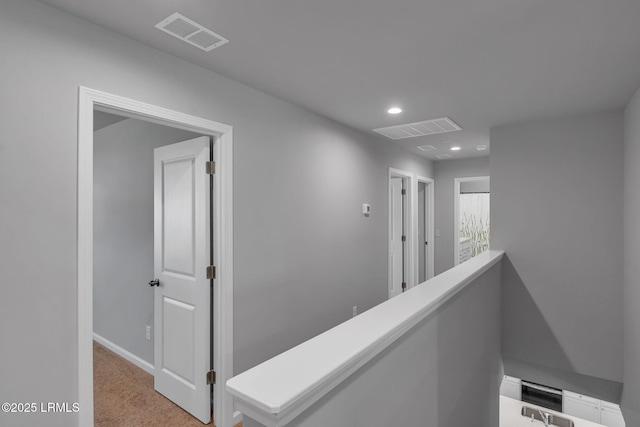 hall with recessed lighting, an upstairs landing, visible vents, and light colored carpet