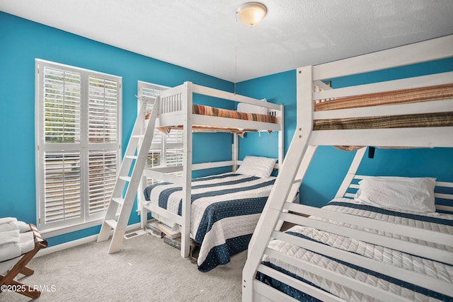 carpeted bedroom featuring a textured ceiling and baseboards