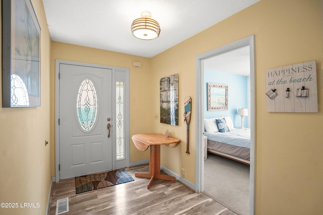 entryway featuring wood finished floors, visible vents, a healthy amount of sunlight, and baseboards