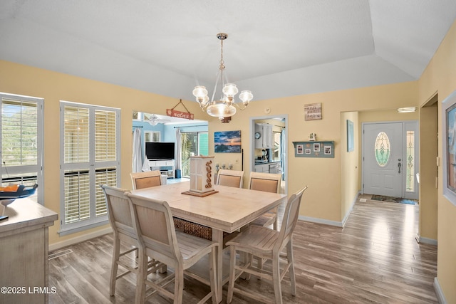dining room featuring plenty of natural light, an inviting chandelier, baseboards, and light wood-style floors