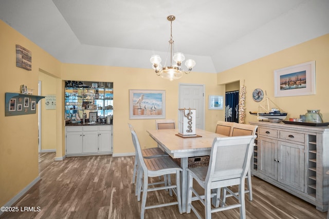 dining space with baseboards, wood finished floors, and an inviting chandelier