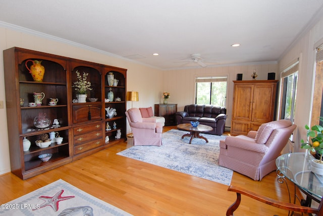 living area with crown molding, ceiling fan, and light wood-type flooring