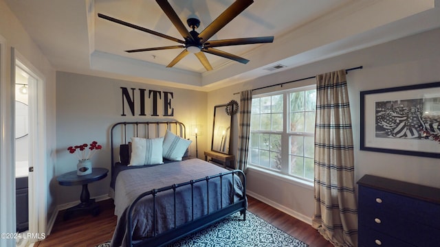 bedroom featuring dark hardwood / wood-style flooring, crown molding, ceiling fan, and a tray ceiling