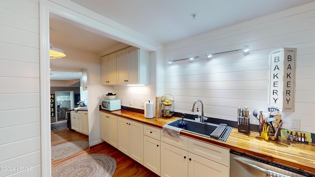 kitchen with dark wood-type flooring, wood counters, dishwasher, and sink