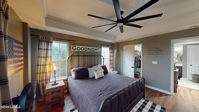 bedroom featuring hardwood / wood-style floors, a tray ceiling, a closet, and ceiling fan