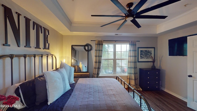 bedroom with dark hardwood / wood-style flooring, crown molding, ceiling fan, and a tray ceiling