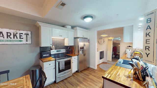 kitchen featuring white cabinetry, backsplash, stainless steel appliances, and wooden counters