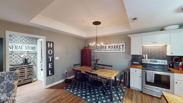 kitchen with butcher block counters, white cabinets, dark hardwood / wood-style flooring, electric range, and a raised ceiling