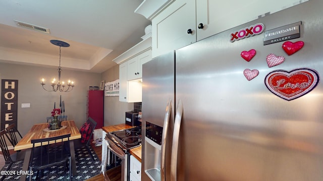 kitchen featuring butcher block countertops, stainless steel appliances, a notable chandelier, a tray ceiling, and white cabinets