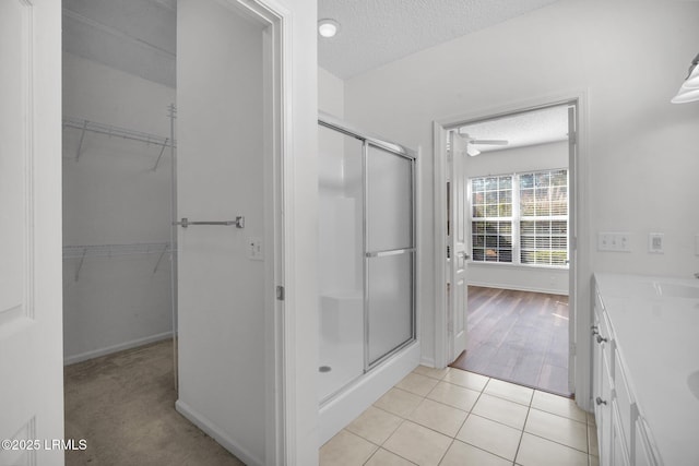 bathroom with tile patterned floors, an enclosed shower, a textured ceiling, and vanity