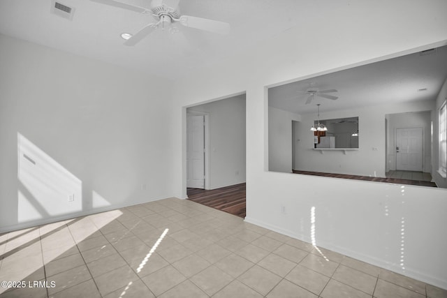 unfurnished room featuring ceiling fan with notable chandelier and light tile patterned floors