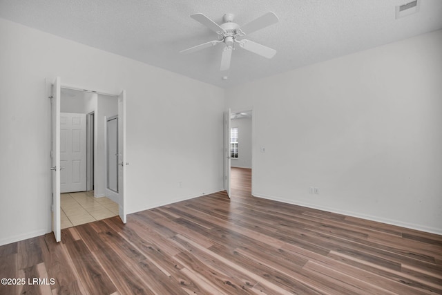 empty room featuring a textured ceiling, wood-type flooring, and ceiling fan