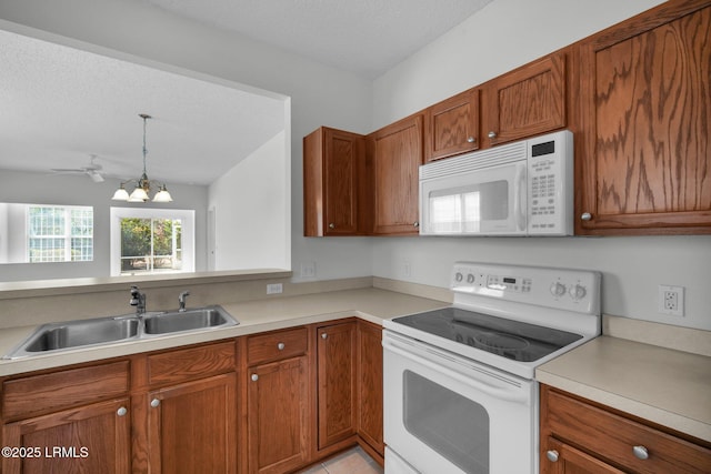 kitchen featuring pendant lighting, sink, white appliances, light tile patterned floors, and a textured ceiling