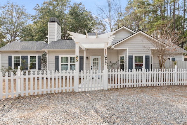 view of front of house featuring a fenced front yard, a chimney, and a shingled roof