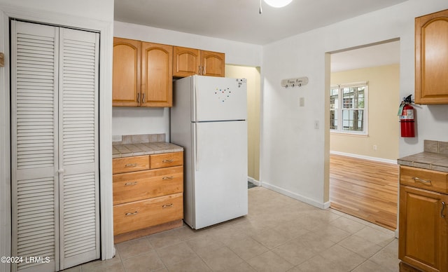 kitchen with white refrigerator, tile countertops, and light tile patterned floors