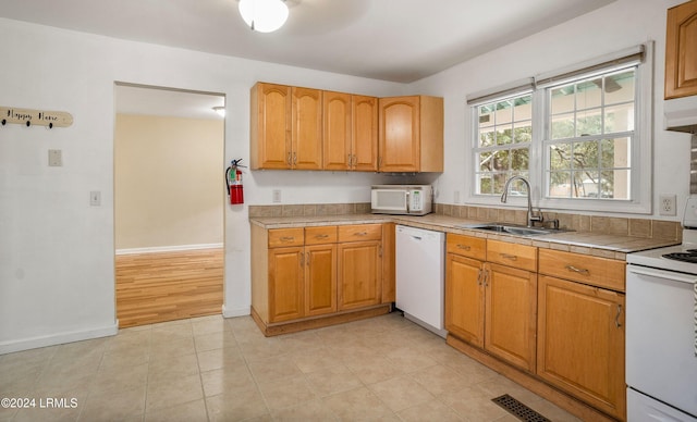 kitchen featuring sink, white appliances, tile counters, and light tile patterned floors