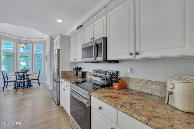 kitchen featuring appliances with stainless steel finishes, white cabinets, hanging light fixtures, crown molding, and light stone countertops