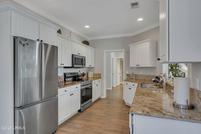 kitchen featuring stainless steel appliances, sink, white cabinets, and light hardwood / wood-style flooring