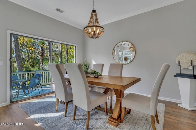 dining area with an inviting chandelier, hardwood / wood-style flooring, and ornamental molding