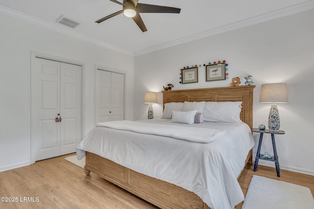 bedroom featuring multiple closets, ceiling fan, crown molding, and light wood-type flooring