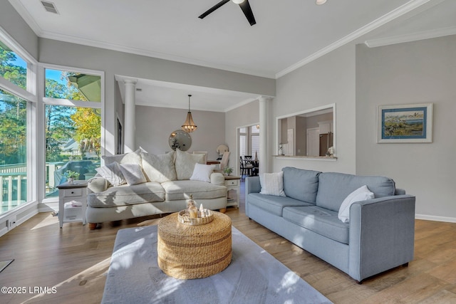 living room featuring plenty of natural light, light hardwood / wood-style floors, and decorative columns