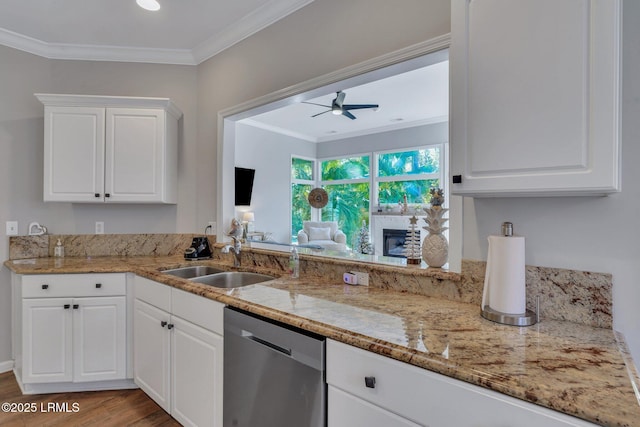 kitchen featuring light stone counters, sink, stainless steel dishwasher, and white cabinets