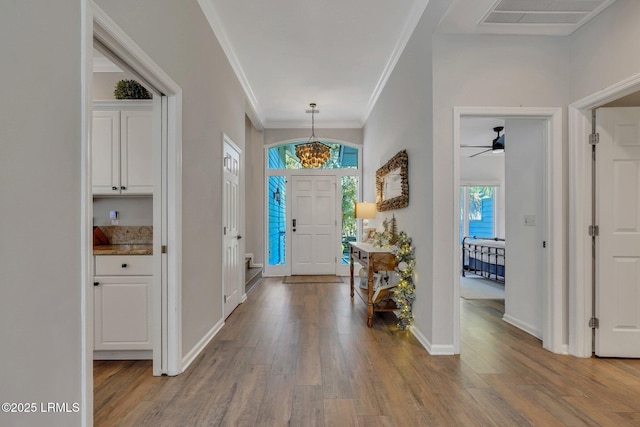 entryway with ornamental molding and light hardwood / wood-style floors