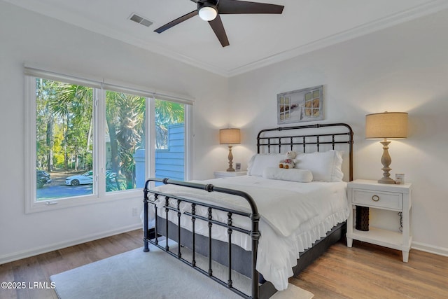 bedroom with wood-type flooring, ornamental molding, and ceiling fan