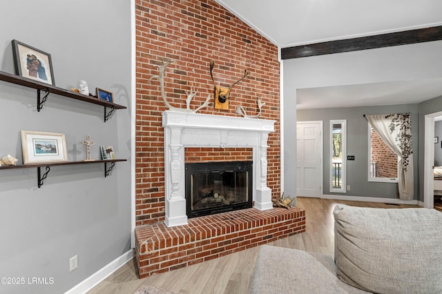 living room featuring a brick fireplace, baseboards, vaulted ceiling, and wood finished floors