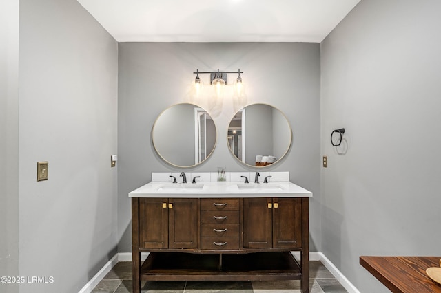 full bathroom featuring double vanity, baseboards, and a sink