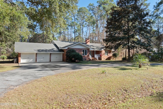 single story home featuring a garage, a chimney, a front lawn, and aphalt driveway