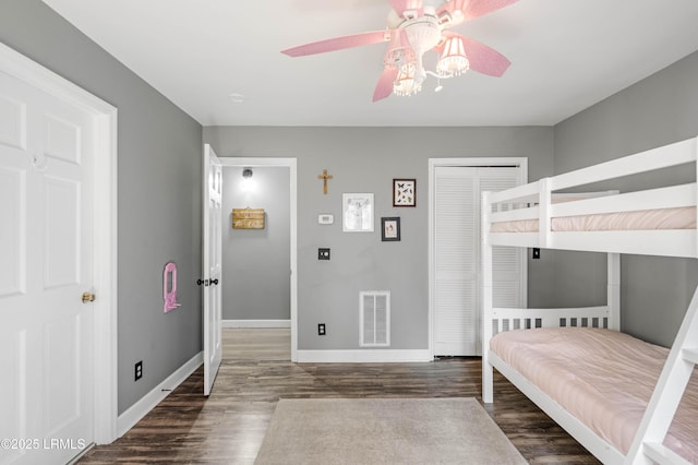 unfurnished bedroom featuring ceiling fan, dark wood-style flooring, visible vents, baseboards, and a closet