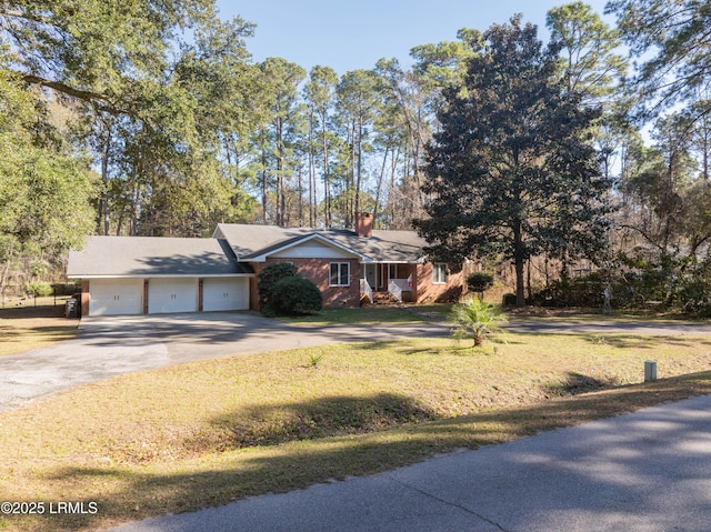 view of front of home featuring a garage, a chimney, concrete driveway, and a front yard