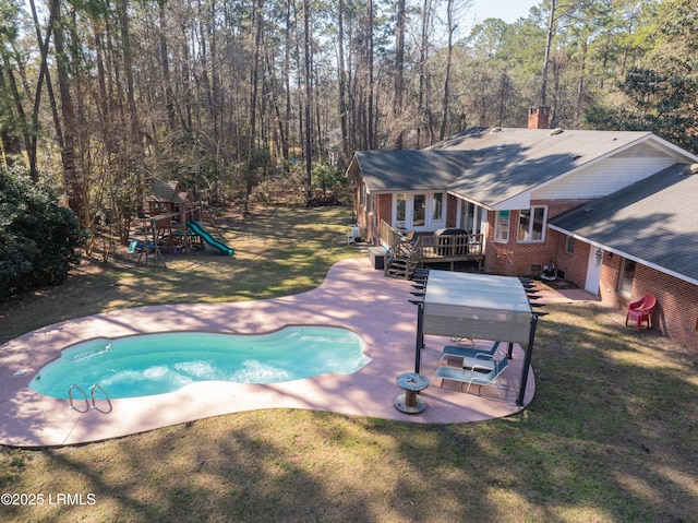 outdoor pool with a patio area, a lawn, a playground, and a wooden deck