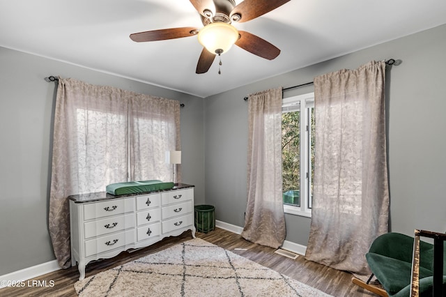 bedroom featuring ceiling fan, wood finished floors, visible vents, and baseboards