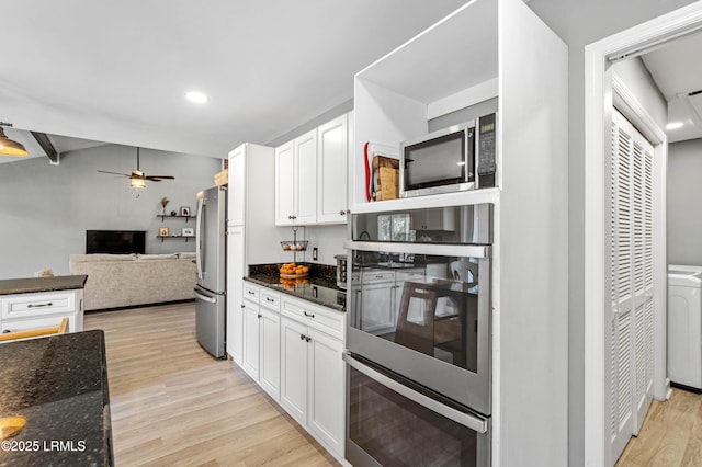 kitchen with light wood-type flooring, white cabinets, stainless steel appliances, and dark stone counters