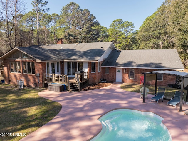 rear view of property with a patio, brick siding, a lawn, a wooden deck, and an outdoor pool