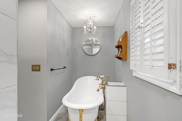 full bath featuring a notable chandelier, a freestanding bath, and baseboards