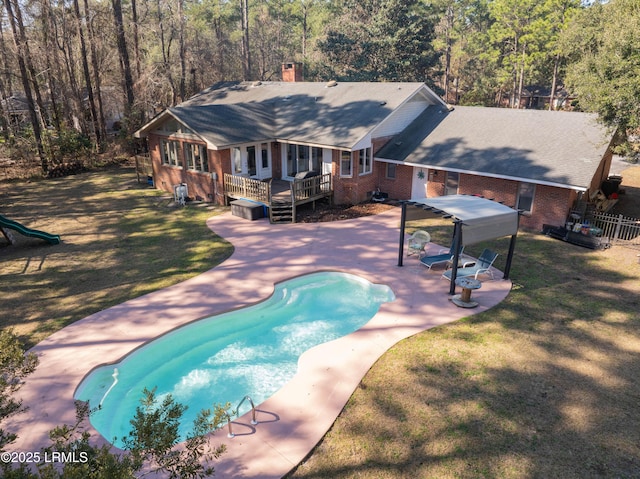 view of pool with a patio, fence, a lawn, a wooden deck, and a fenced in pool