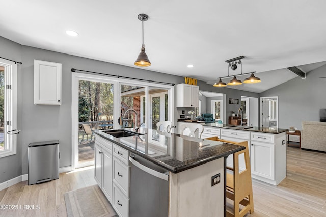 kitchen featuring a center island with sink, lofted ceiling with beams, a peninsula, stainless steel dishwasher, and a sink