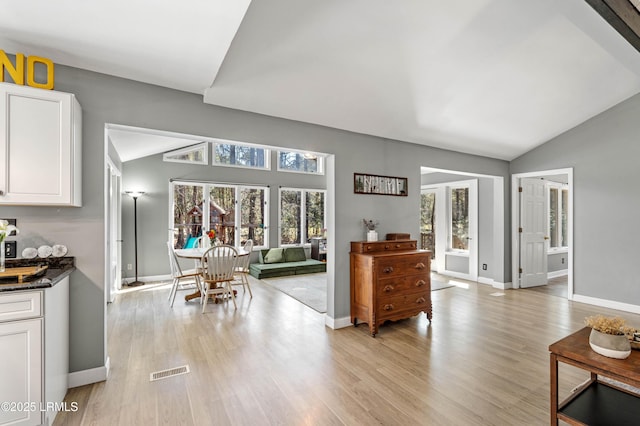 interior space featuring lofted ceiling, light wood-style flooring, and baseboards