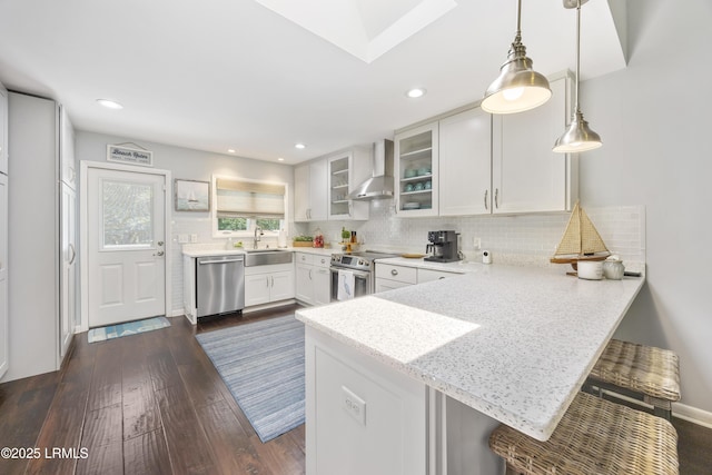 8 Bradley Beach Rd, Hilton Head Island, SC 29928 - kitchen featuring stainless steel appliances, wall chimney range hood, a peninsula, white cabinets, and a sink